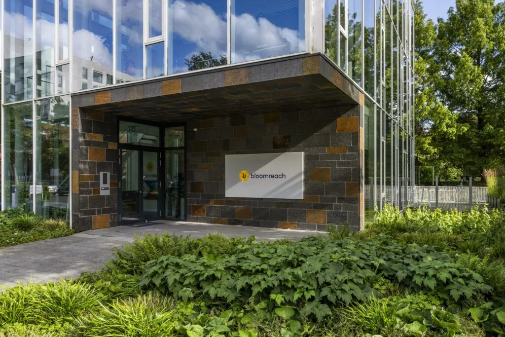 Entree van het kantoorgebouw van Bloomreach aan de Fred. Roeskestraat, met moderne gevel en omliggende beplanting.